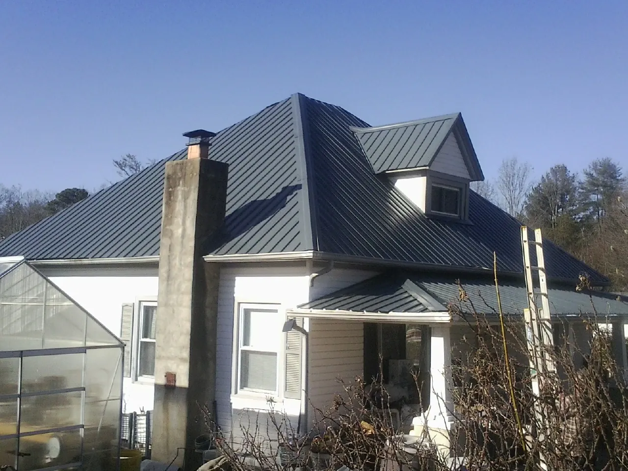 Dark blue standing seam metal roof on a white farmhouse with dormer — Slate & Tile Roof Repair by Roofing Brothers in Moravian Falls