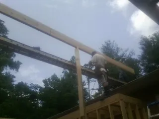 Carpenter setting a ridge beam over a new addition frame — Ice Dam Removal by Roofing Brothers in Moravian Falls