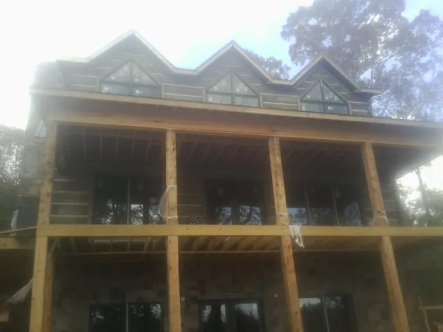 Dormers and porch framing on a large log home under construction — Roof Coating work by our crew in Moravian Falls