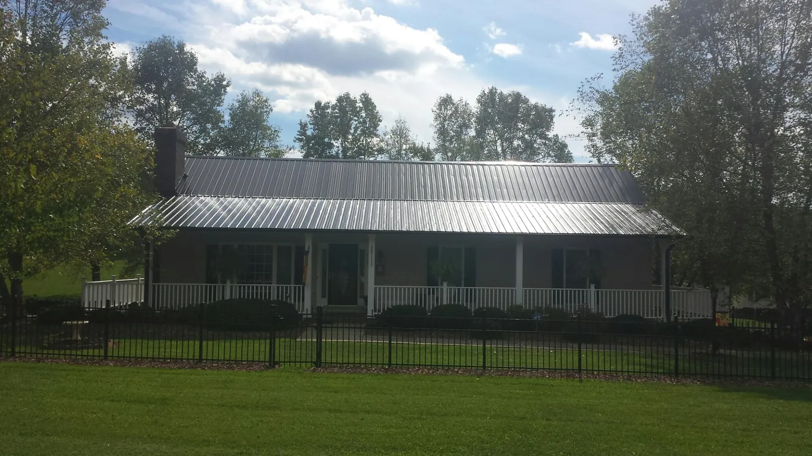 Gray metal roof on a brick ranch with a full width front porch — Gutter Guard Installation work by our crew in Moravian Falls